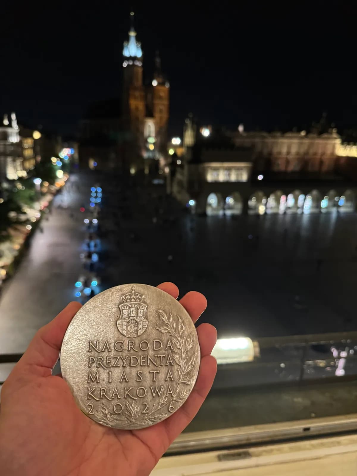 Medal Nagrody Prezydenta Miasta Krakowa na tle nocnego Rynku Głównego